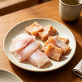Pale fish slices and golden cubes plated on a white dish
